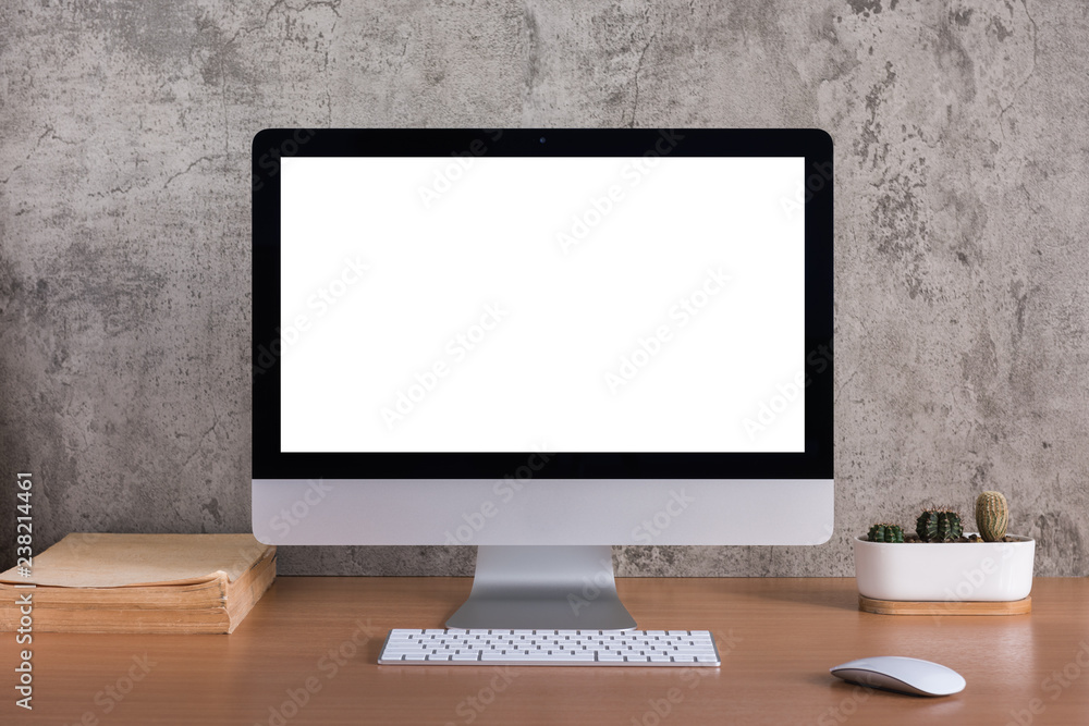 Blank screen of all in one computer with old book and cactus vase on ...