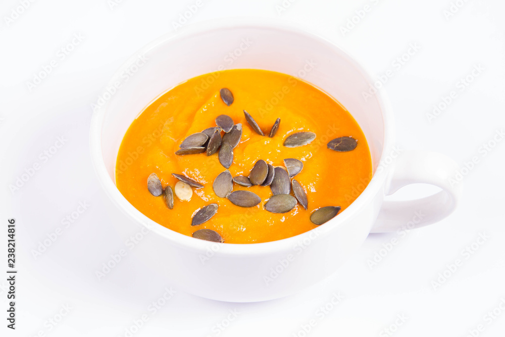 Pumpkin soup decorated with pumpkin seeds in a bowl on a white background Pumpkin soup decorated with pumpkin seeds in a bowl on a white background