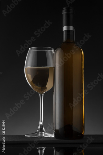 White wine bottle and glass on the black background