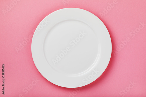 White ceramic plate on a pink background, top view. Food background photo