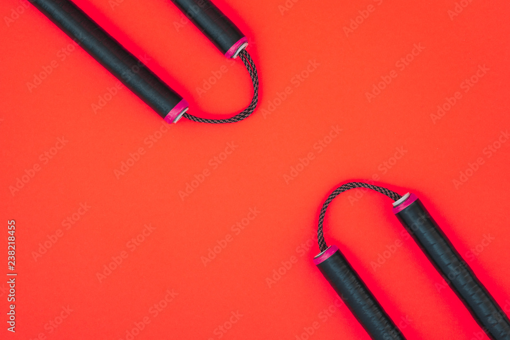 Training nunchaku isolated on a red background. Asian Nunchaku weapon