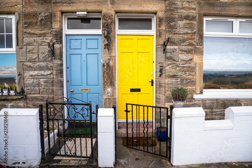 Colourful Wooden Front Doors of two traditional British Terraced Houses. One Door is Light Blue while the other is Bright Yellow. photo