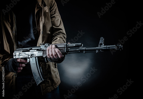 Dangerous armed terrorist with mask and machine gun on dark background. Concept of terrorism and violence.
