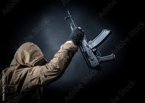 Dangerous armed terrorist with mask and machine gun on dark background. Concept of terrorism and violence. photo