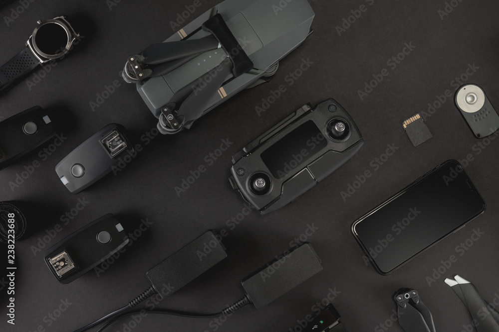 Work space photographer with laptop, digital camera, memory card, action camera, drone, remote controller, phone, VR glasses and camera accessory. Top view on black table background. Work space photographer with laptop, digital camera, memory card, action camera, drone, remote controller, phone, VR glasses and camera accessory. Top view on black table background.
