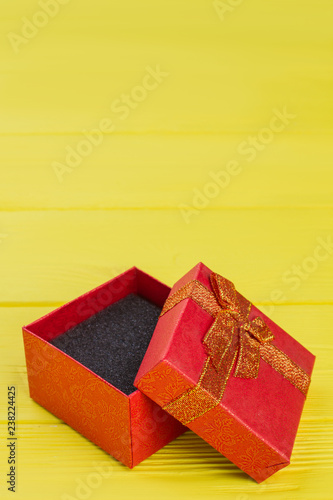 Opened decorative gift box. Copyspace. Yellow wooden background.