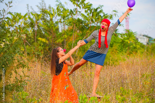 женщина и девочка в костюмах клоуна гуляют на природе 