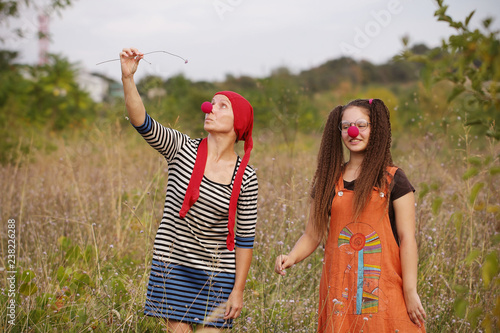 женщина и девочка в костюмах клоуна гуляют на природе 