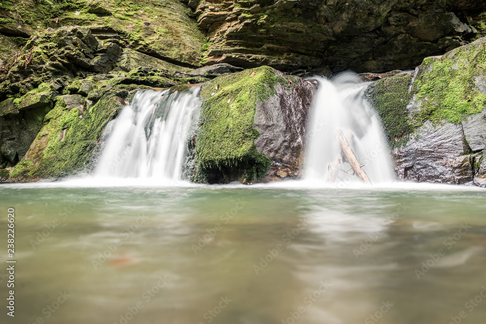 Fototapeta premium Small mountain waterfall on the rocks covered with moss in the forest