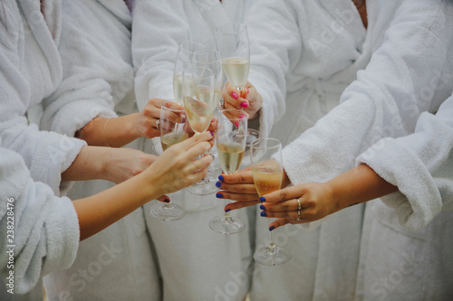 Crop women in bathrobes clinking glasses of champagne photo