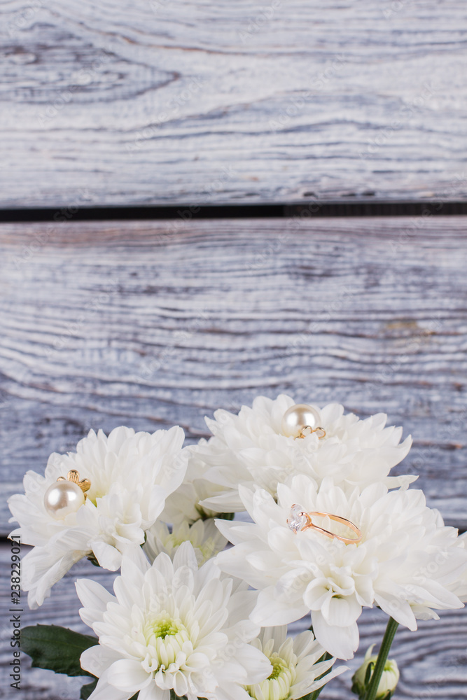 Fototapeta premium White chrysanthemum flowers on wooden background. Marriage proposal with bouquet of flowers and golden ring. Vintage effect.
