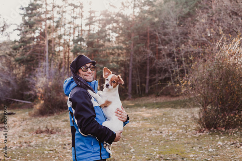 Man with his cute small dog standing in the forest at sunset. healthy lifestyle. Hiking © Eva