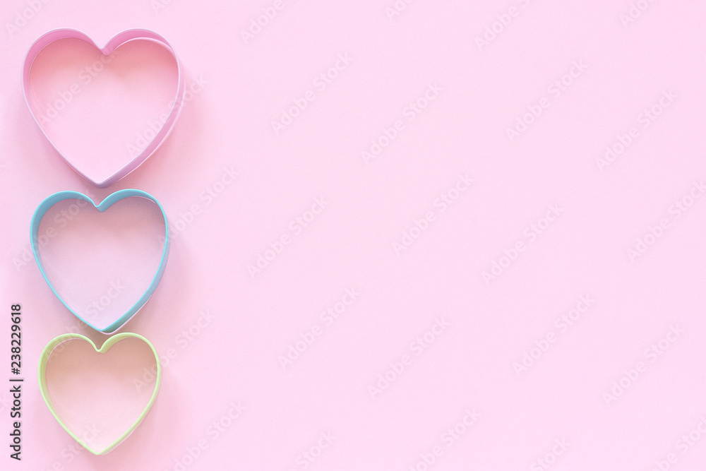 Colorful cutters cookies in heart shape on pastel pink background. Concept Valentine's card. Top view Copy space for text.