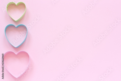 Colorful cutters cookies in heart shape on pastel pink background. Concept Valentine's card. Top view Copy space for text. © IRINA