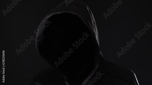 Unrecognizable faceless spooky hooded hooligan, low key photo