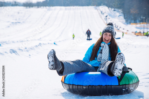 young smiling girl ride sleigh snow tubing hill winter activity