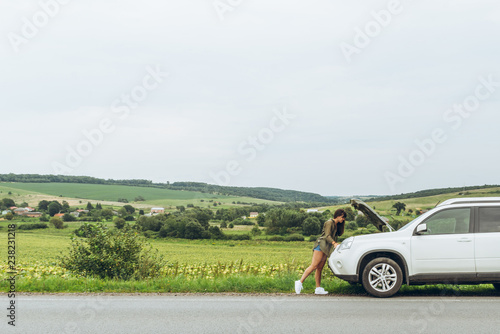 Fototapeta Naklejka Na Ścianę i Meble -  woman stand at roadside near broken car with opened hood