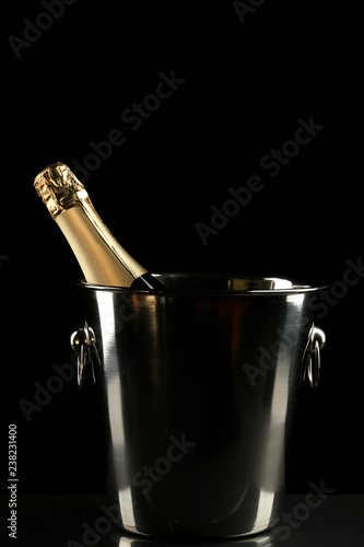 Champagne bottle in bucket on black background