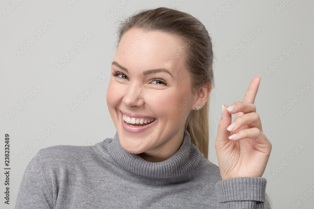 Junge lächelnde Frau im grauen Pulli hat eine Idee Junge lächelnde Frau im grauen Pulli hat eine Idee