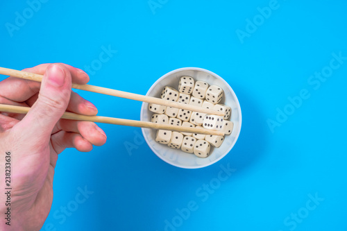 dices in a white bowl with chopsticks on a blue background