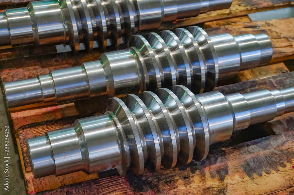 The worm shaft after machining lies on a wooden rack and is ready for use in mechanical