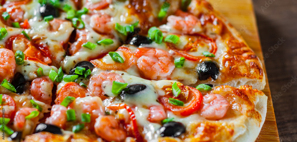 Pizza with Mozzarella cheese, olives, shrimps, tomato sauce, Spices and Fresh green onion. Italian pizza on wooden table background