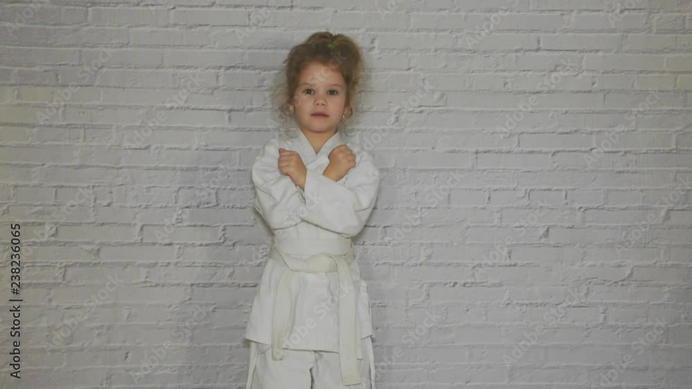 girl, a child in a kimono on karate training works out blows and greeting girl, a child in a kimono on karate training works out blows and greeting