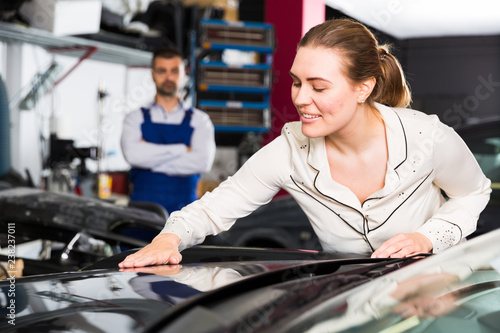 Female client delighting with car after repainting photo