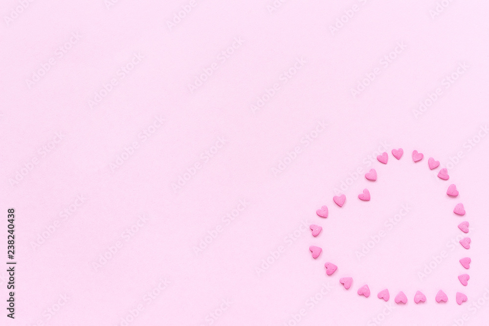 Pink confectionery sprinkles in heart shape on pastel pink background. Concept Valentine's card. Top view Copy space for text