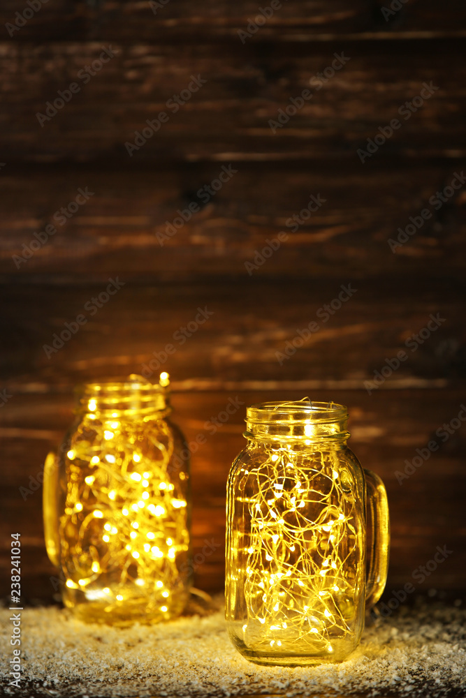 Garland lights in glass jars on brown background Garland lights in glass jars on brown background