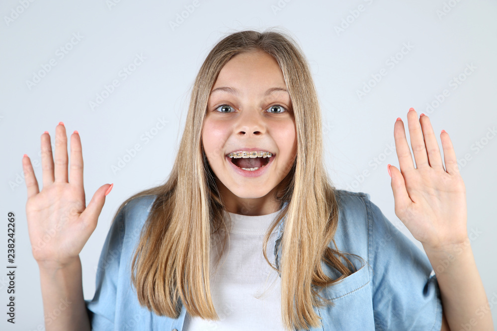 Young smiling girl with dental braces on grey background Young smiling girl with dental braces on grey background