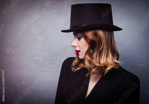 Style and mystique redhead girl in top hat on grey background