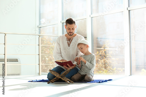 Photography Muslim man and his son reading Koran together indoors