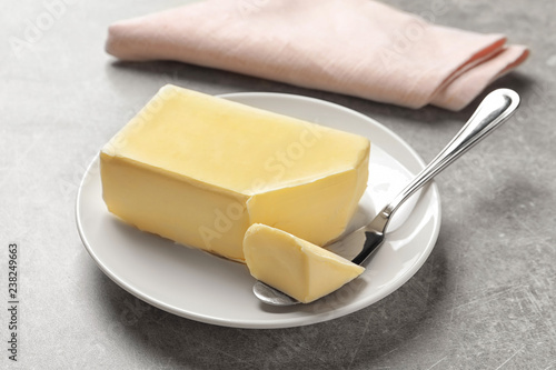 Plate with fresh butter and knife on table