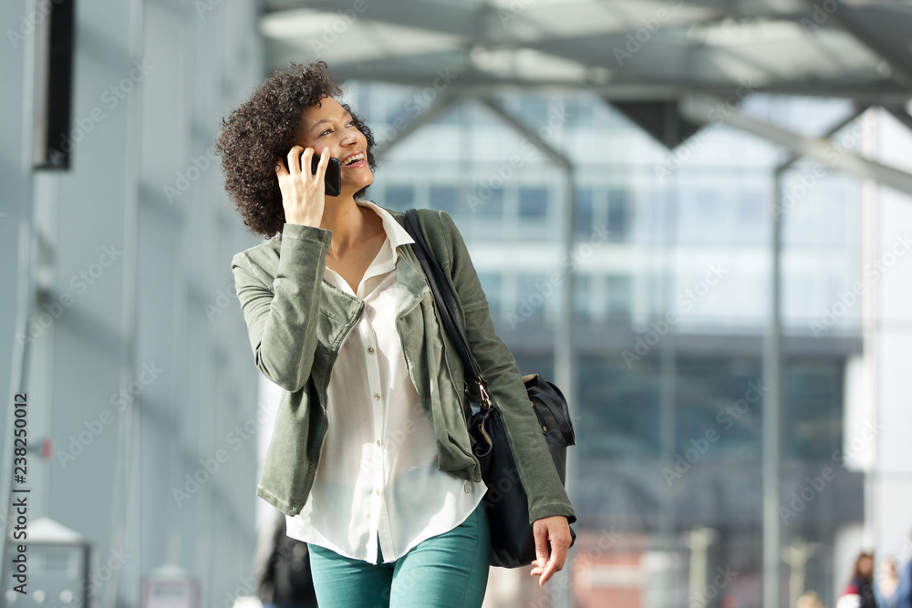 Fototapeta premium smiling african american woman talking with mobile phone
