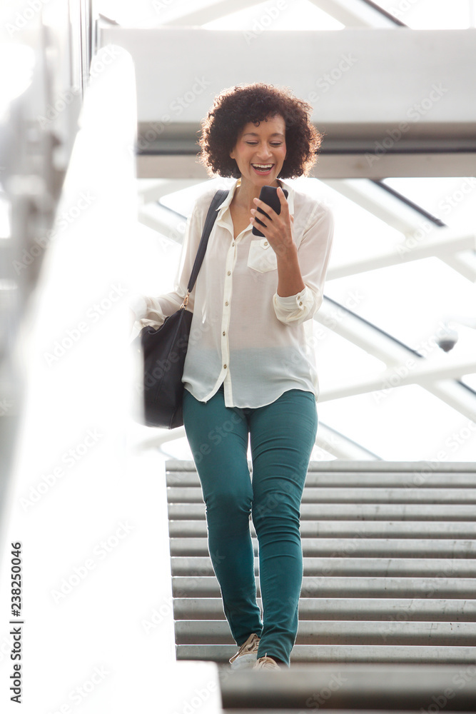 Full body african american woman walking down stairs with cellphone Full body african american woman walking down stairs with cellphone