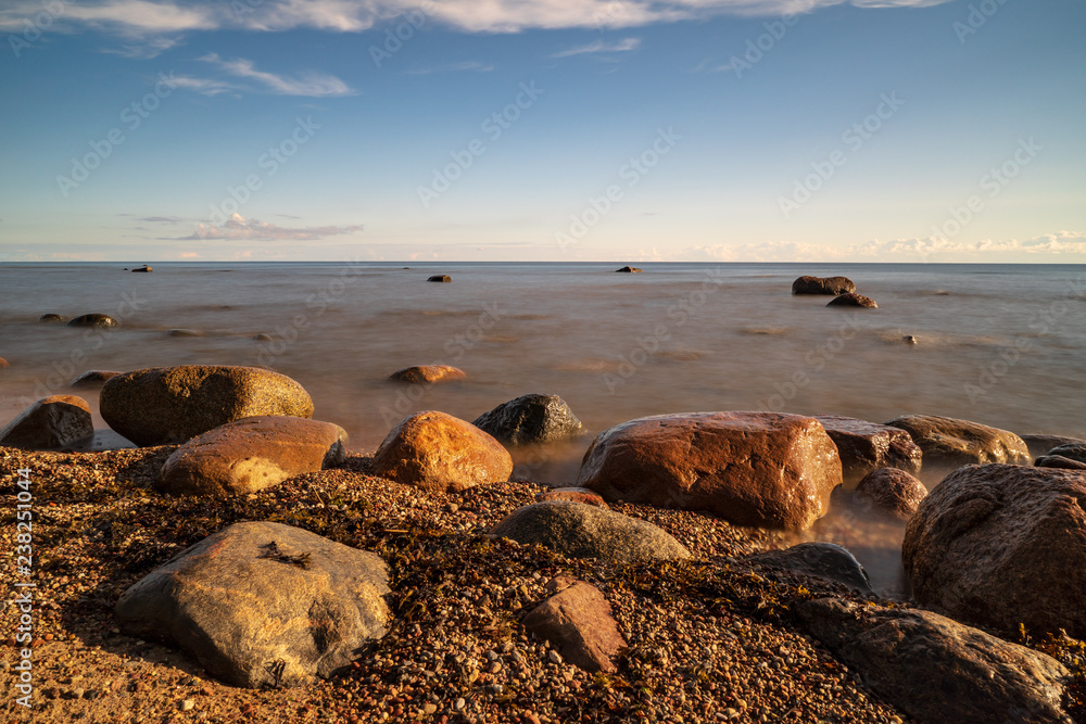 rock covered beach in countryside in Latvia, large rocks in water