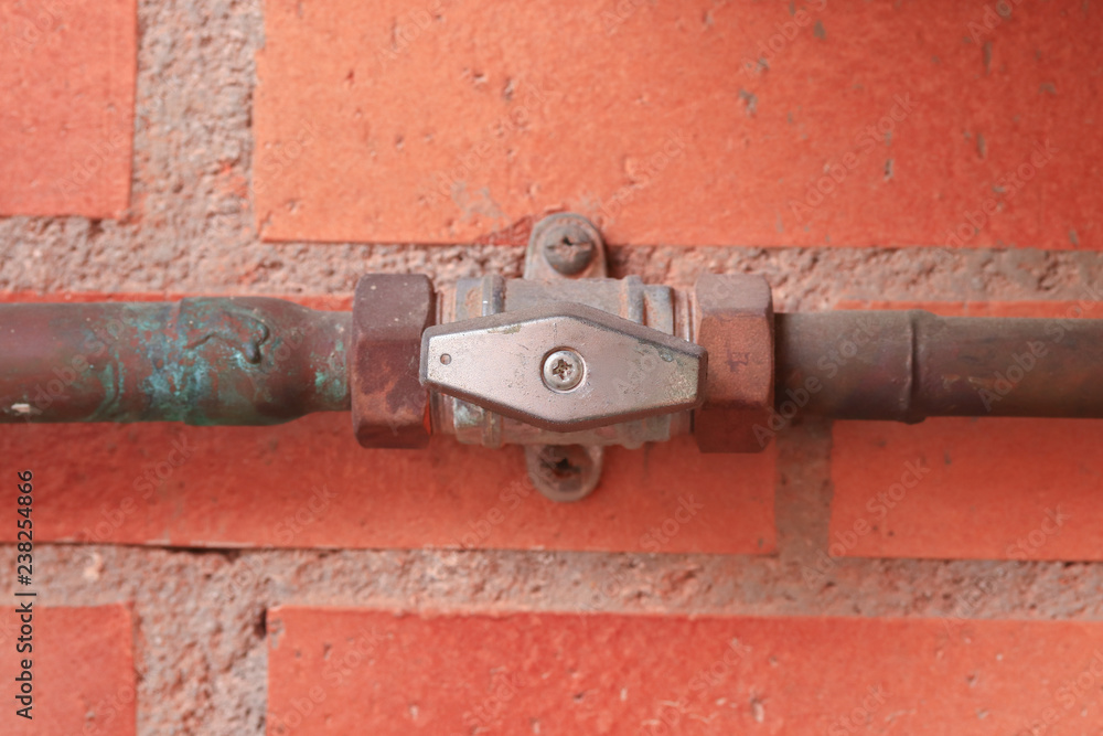 Gas pipes and a valve against a red brick wall. Gas pipes and a valve against a red brick wall.
