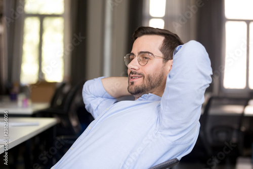 Confident businessman in glasses relaxing leaning back in chair at workplace, looking in distance, break after finish work, business achievement, feeling satisfied, thinking about business strategy
