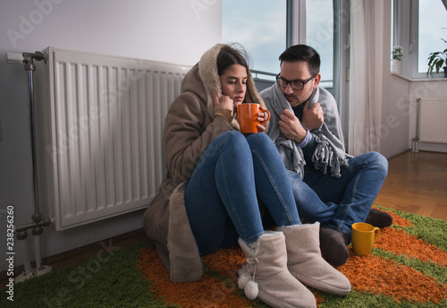 Couple sitting beside radiator and freezing photo