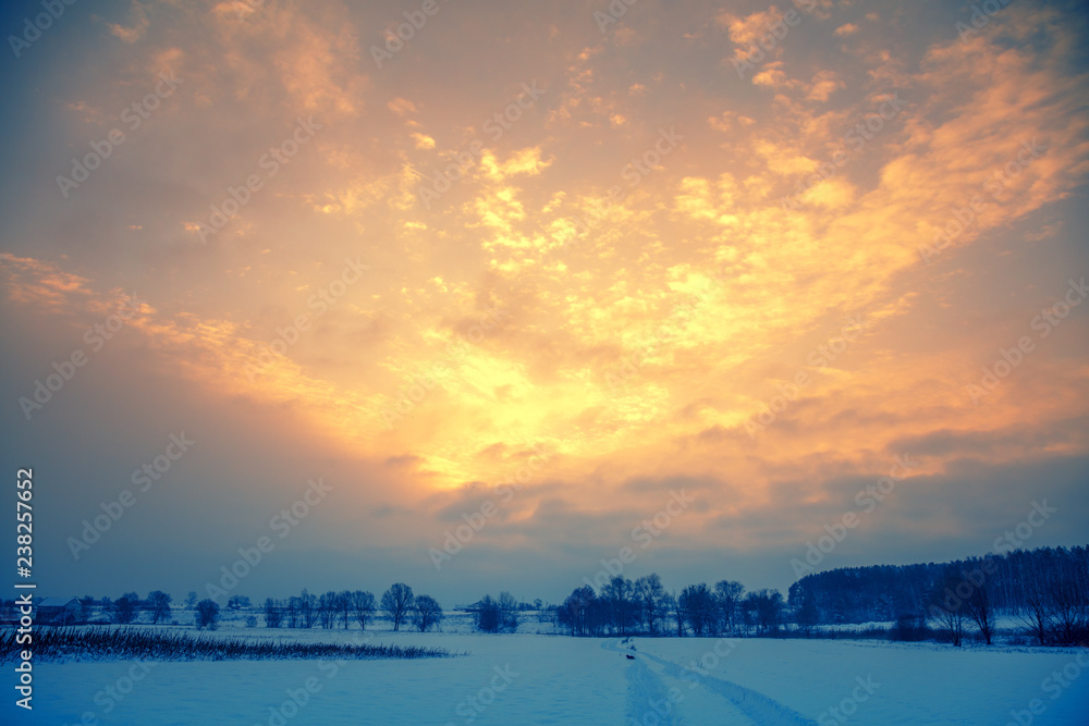 Sunset over the countryside. Winter snow landscapes. Blazing sunset sky over a snowy field Sunset over the countryside. Winter snow landscapes. Blazing sunset sky over a snowy field