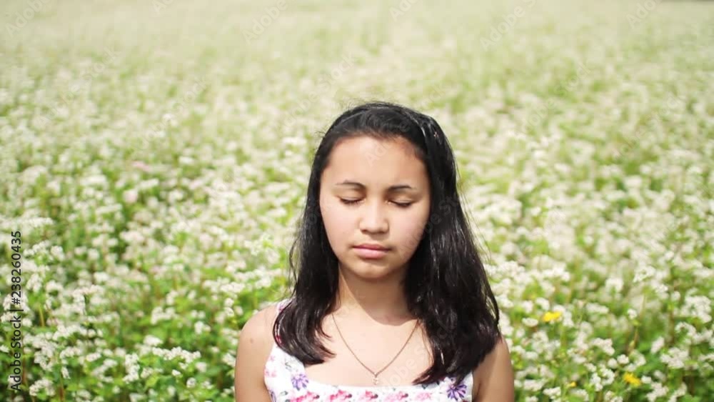 Blurred image of lovely brunette woman with closed eyes enjoying the scent of blooming white flowers.Flowered field on the background.Tenderness, calmness, relaxation, silence. Female portrait Blurred image of lovely brunette woman with closed eyes enjoying the scent of blooming white flowers.Flowered field on the background.Tenderness, calmness, relaxation, silence. Female portrait