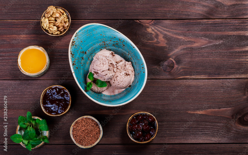 Chocolate ice cream scoops in bowl with mint leaves on wooden background. Top view