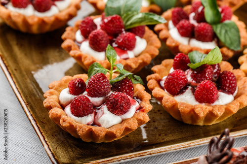 Fruit tart with raspberries and cream, cakes and sweetness on holiday background. Delicious dessert and candy bar.