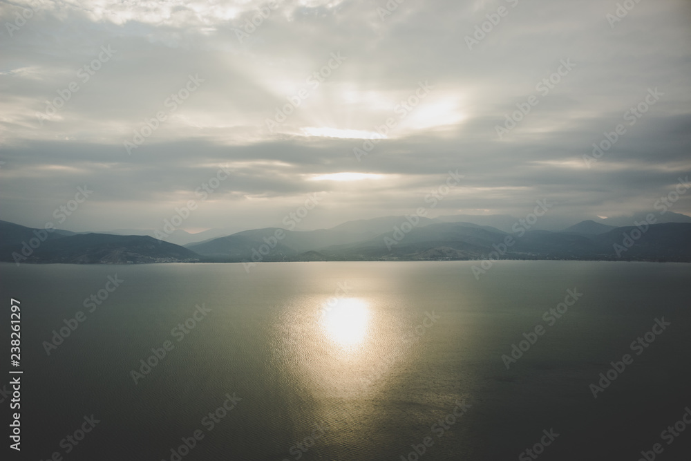 soft focus abstract morning foggy time mountain silhouette landscape in calm sea bay water surface with reflection of sun rise light