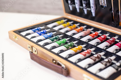 Opened wooden suitcase with watercolor tubes and brushes