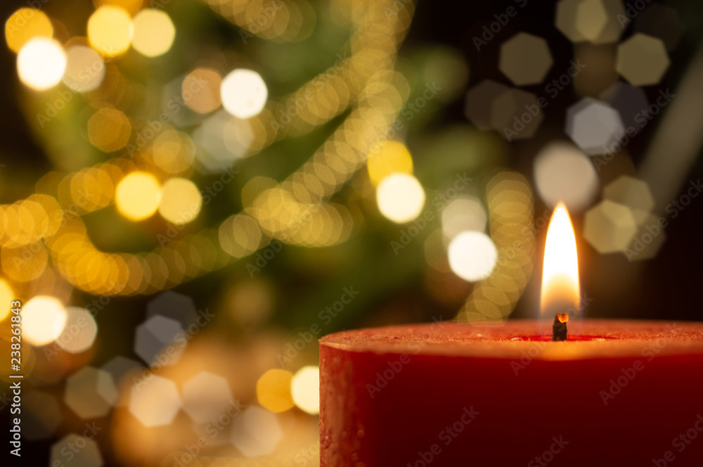 Lighted candle with the blurred Xmas tree on background Lighted candle with the blurred Xmas tree on background