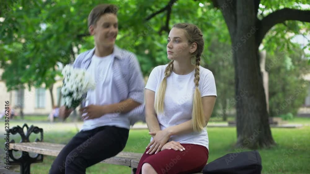 Amorous teenager jumping over bench and presenting flowers to girlfriend, date Amorous teenager jumping over bench and presenting flowers to girlfriend, date