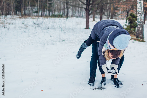 Guy giving his girlfriend piggyback in winter forest. Young loving couple having fun outdoors