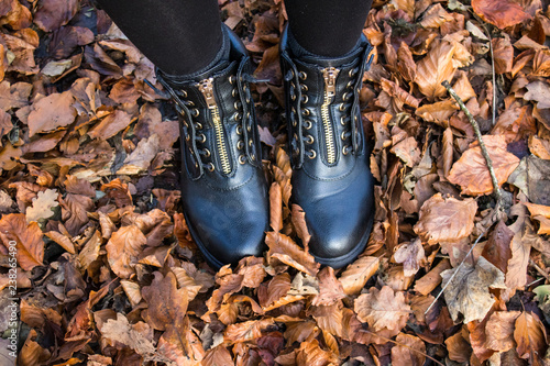 Woman wearing black hiking boots and walking in the autumn leaves